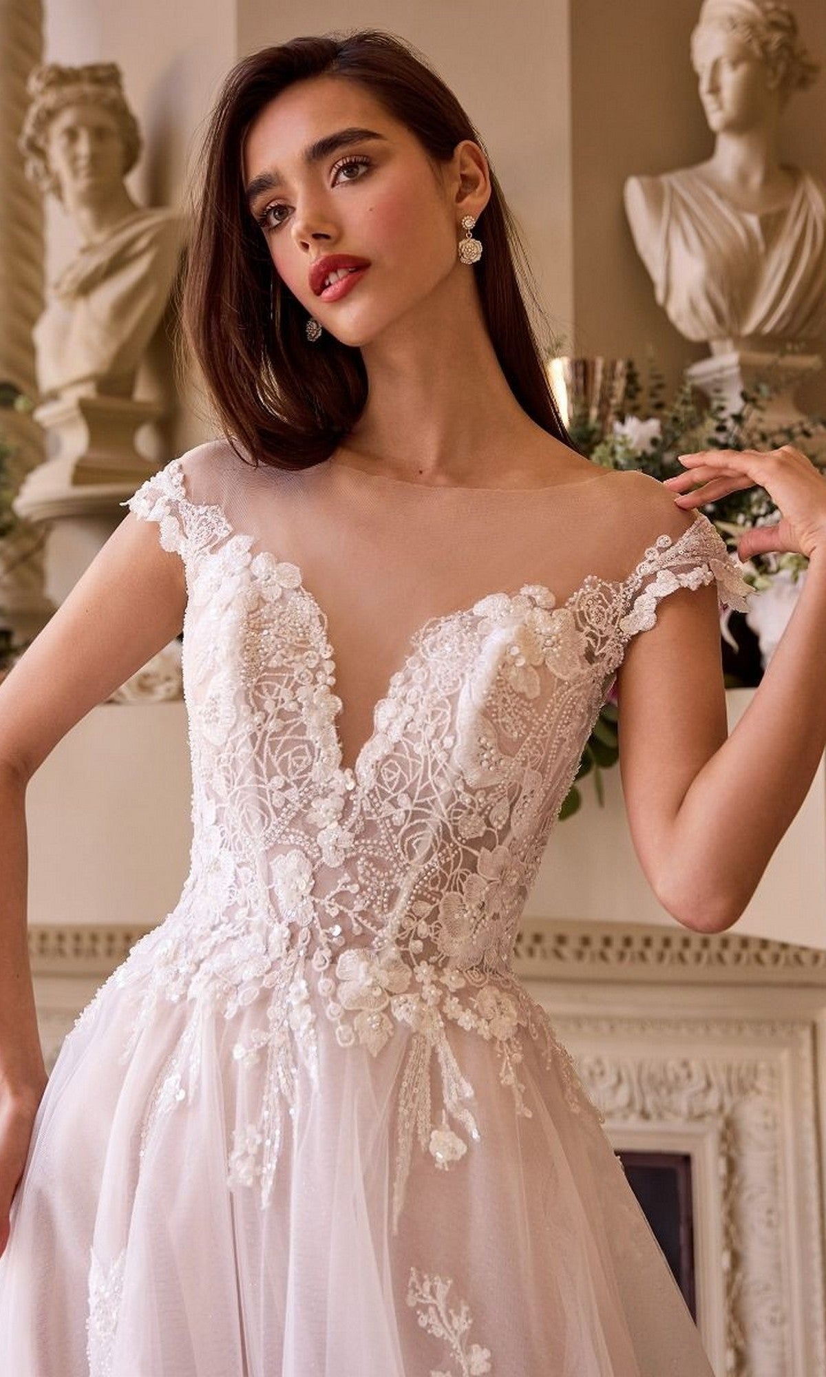 A woman in the Andrea and Leo WL038 long wedding dress stands indoors near classical statues and ornate decor.